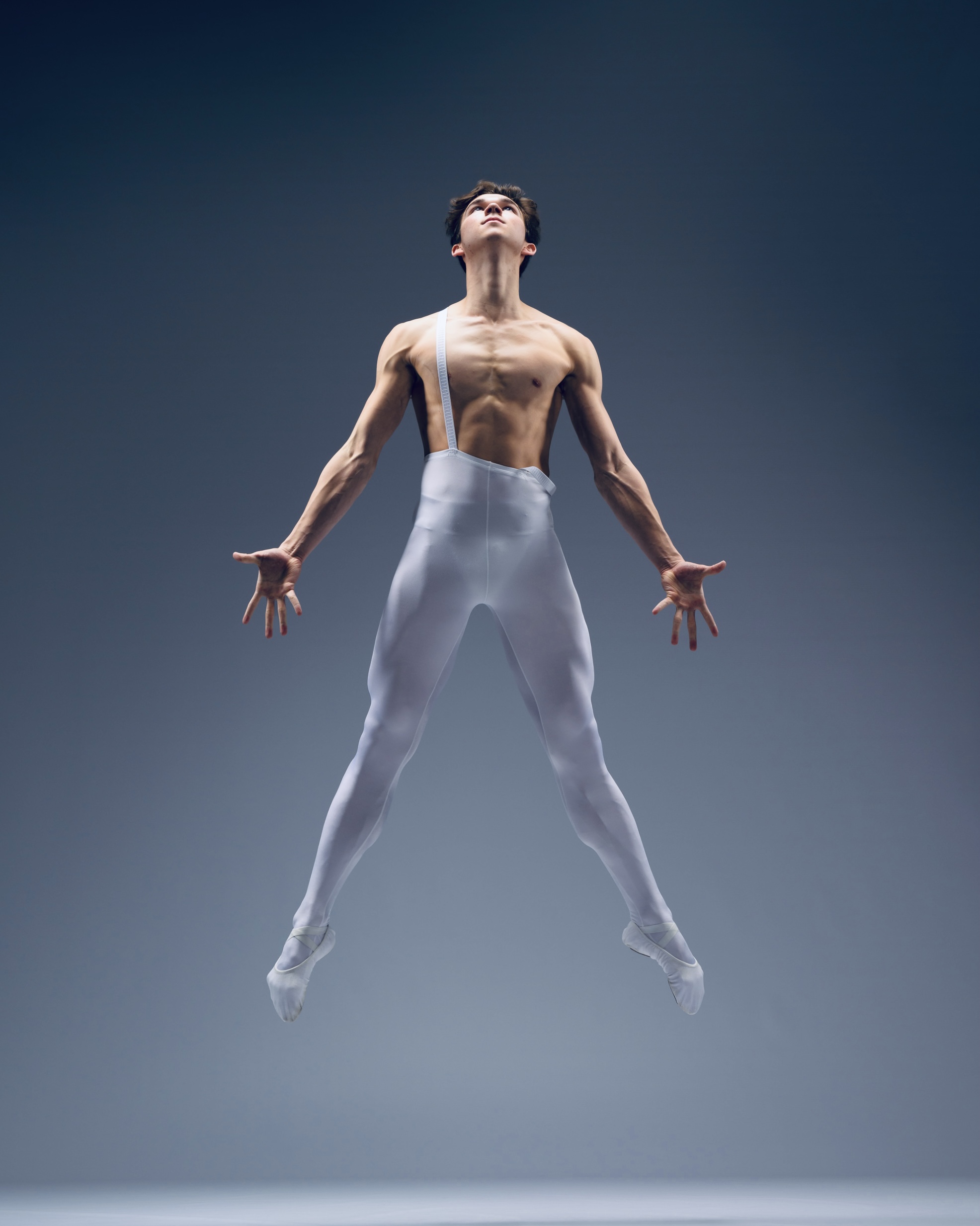 Karl Pil in an extended ballet line on a dark stage